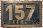 Hildesheim Peiner Kreiseisenbahn HPKE. 1929 - 1949 Braunschweig-Schninger Eisenbahn, dort Betriebsnummer 153. 1949 - 1965 im Besitz der HPKE. 1964 in Hildesheim-Nord abgestellt. 1965 ausgemustert und verschrottet. Eine ELNA 5 Maschine. Umgebautes Messinggussschild: Vorher 153 B.S.E. Ziffer 3 und Buchstaben abgeschliffen und durch eine geschraubte Ms Ziffer 7 und genietete Ms Buchstaben ersetzt. BxH = 381 x 250 mm.