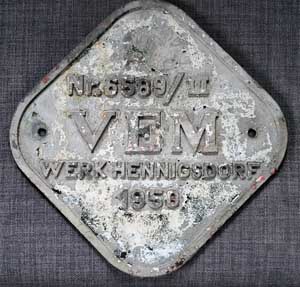 Fabrikschild LEW unter VEM (Vereinigung Volkseigener Betriebe des Elektro-Maschinenbaues), Hennigsdorf (Berlin). Fabriknummer: 6589, Baujahr: 1950. Aluminiumguss, rechteckig, glatt mit Rand. BxH = 420 x 420mm. Das sch�ne Fabrikschild ist von einer Tagebauelektrolokomotive, 80t, Bo'Bo'-el, 1524 mm Spurweite. Neu geliefert als Reparation UdSSR /=> Hydropower Coal Mine Fuxin [China] "6589". Erworben wurde das Schild 2003 in Fuxin. 