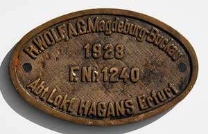 Fabrikschild R. Wolf AG, Magdeburg-Buckau, Abt. Lokfabrik Hagans Erfurt. Fabriknummer: 1240, Baujahr: 1928. Messingguss oval, Riffelgrund mit Rand. BxH =  x  mm. Das sch�ne Fabrikschild ist von der DRG/DB 64 084.